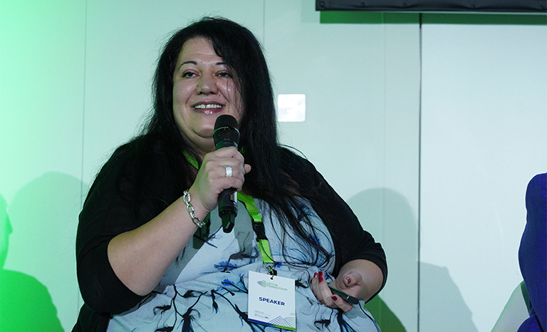 Мария Накова държаща микрофон и говори по време на събитието GREEN WEEK 2023: "Зеленият преход в страните от Централна и Източна Европа 2023", събитие на тема "ЗЕЛЕНИТЕ ИНОВАЦИИ В СТРОИТЕЛНИЯ СЕКТОР И НОВИЯТ ЕВРОПЕЙСКИ БАУХАУС"