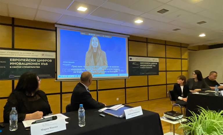 участниците в отркиването на ЕЦИХ, гледащи видео, което се прожектира на презентационна стена.